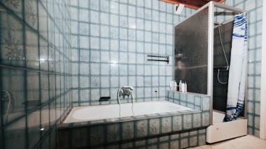 Badrum med blått kakel, duschkabin och badkar