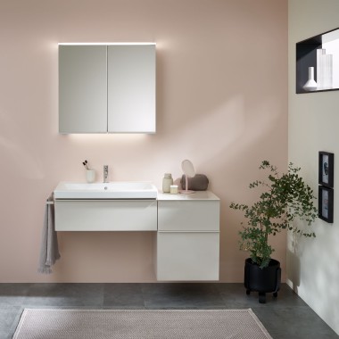 Tvättställ med badrumsmöbler, tvättställ och spegelskåp från Geberit framför en pastellvägg