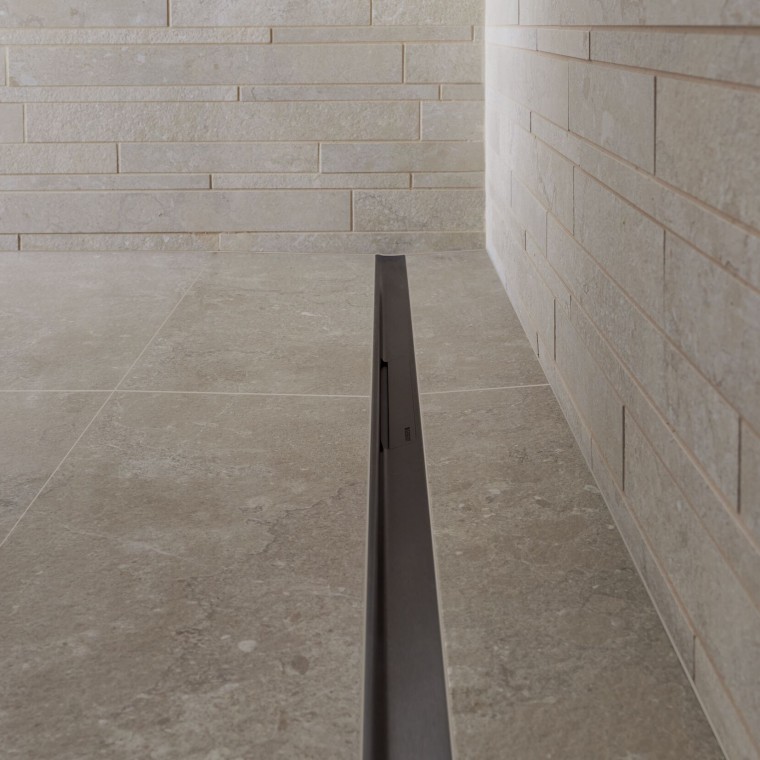 Vattnet rinner bort via en elegant profil i rostfritt stål.