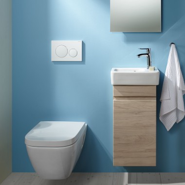 En vägghängd toalett och handfakt med underskåp till en ljus blå vägg