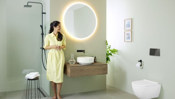 Kvinna i ett badrum med en Geberit Option spegel och ett Geberit VariForm tvättställ