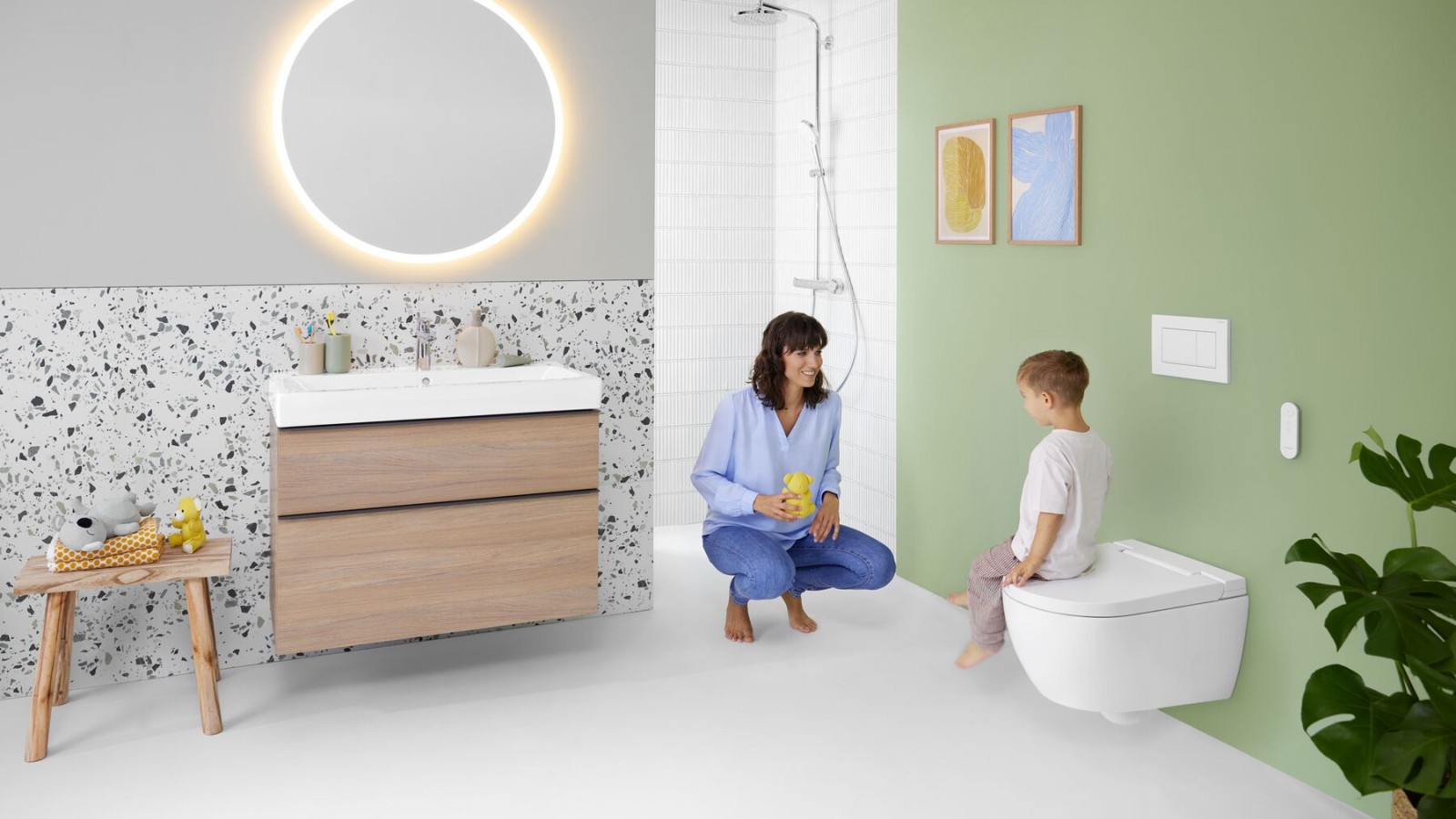 Kvinna och barn i ett badrum med mycket färg och Geberit Option spegel och Geberit AquaClean Alba duschtoalett