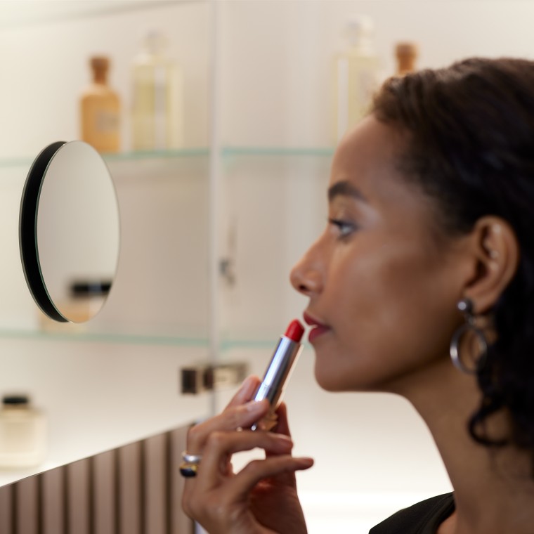 Kvinna som sminkar sig i spegeln