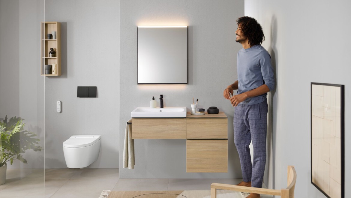 En man står i ett badrum med en AquaClean Sela duschtoalett