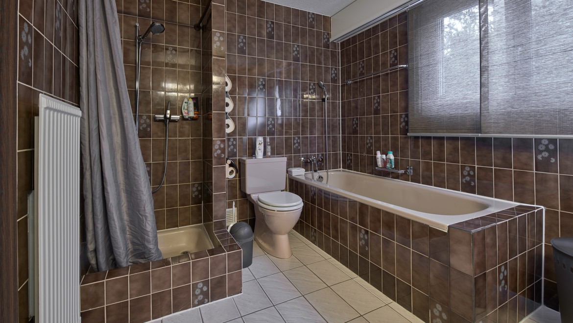 Badrum med en trång duschhörna, badkar och golvstående WC