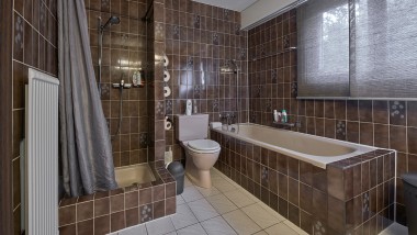 Badrum med liten duschhörna, badkar och golvstående WC