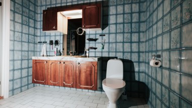 Badrum med blått kakel och golvstående WC