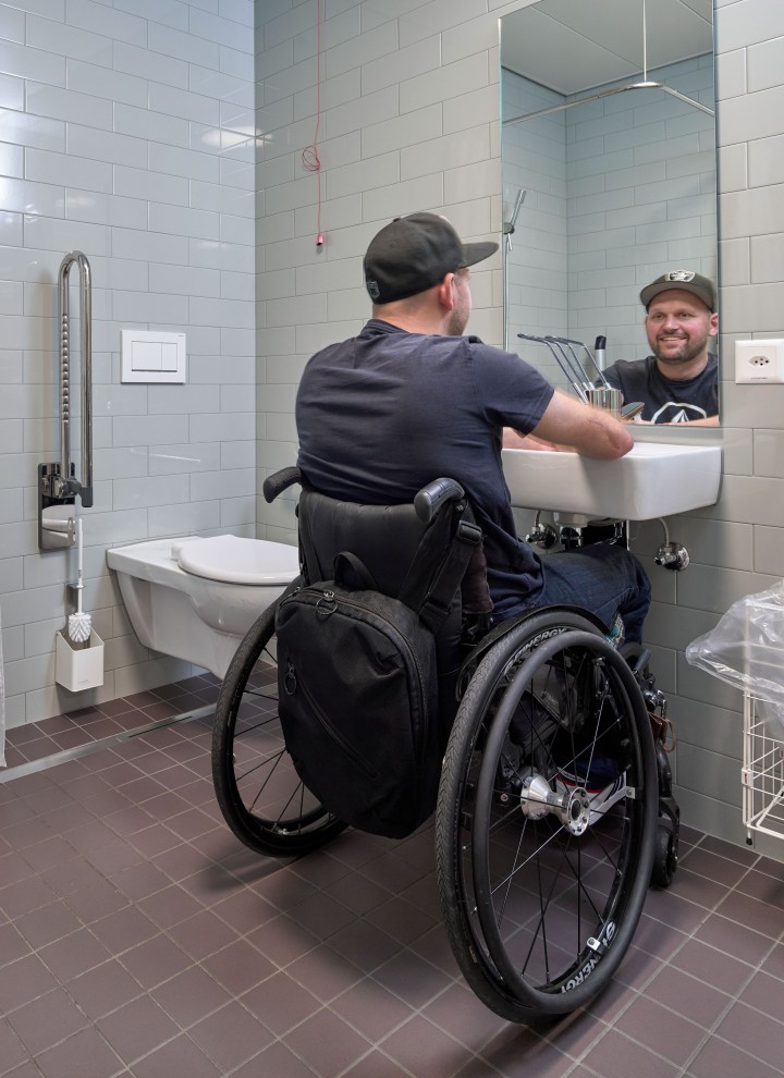 Peter Roos i sin rullstol i ett nivåfritt badrum (© Ben Huggler)