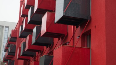 En slående röd fasad med kubiska balkonger på framsidan är ett blickfång på Goldsteinstrasse i Frankfurt am Main (DE) (© Geberit)