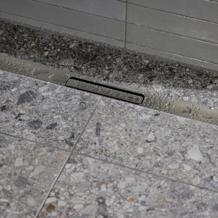 Vattnet rinner via en elegant uppsamlingsprofil i rostfritt stål Vattnet rinner via en elegant uppsamlingsprofil i rostfritt stål